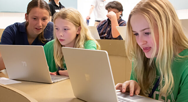 students sitting at laptops learning to code