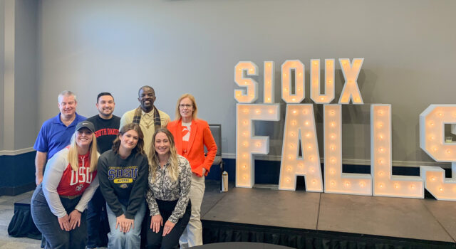 Panelists stand by marquee letters at Summit League tournament
