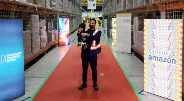 Ash Gill holding child while standing with Amazon signs