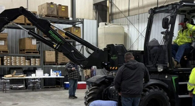 A photo of employees observing a mowing machine