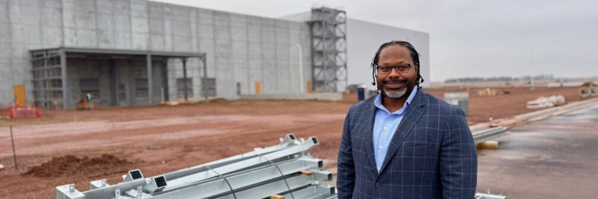 A photo of Sam Douglas in front of a building project