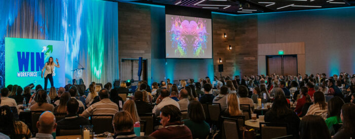 A photo of a woman speaking on a stage at the WIN in Workforce Summit