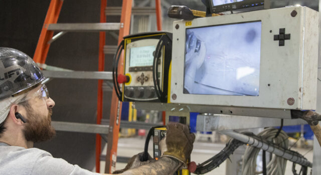 A man looking at a machine screen in a manufacturing facility