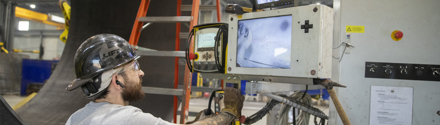A man looking at a machine screen in a manufacturing facility